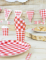 Mise en scène avec assiette et fanions du gobelet en carton festonné vichy pour fête rouge et blanc